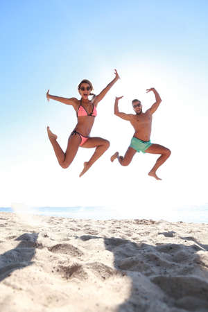 Happy couple jumping on beach.の写真素材