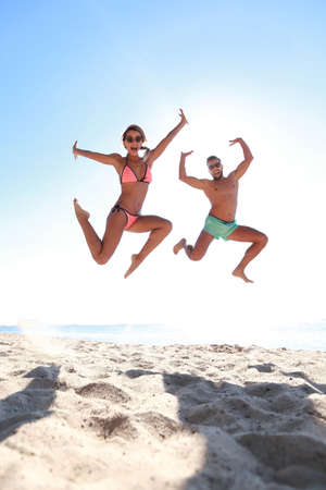 Happy couple jumping on beach.の写真素材