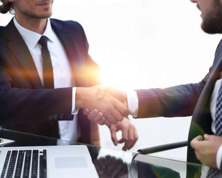 handshake business partners in front of the open laptopの写真素材