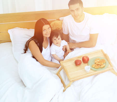 Mother, father, baby on the bed in the roomの写真素材