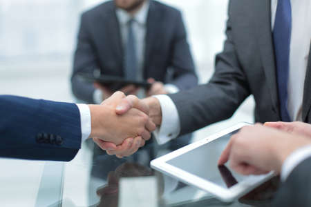 Men shaking hands with smile at office with their coworkers.