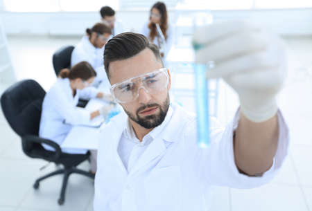 image is blurred. young scientist holding tube with the reagents