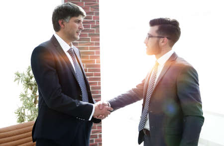businessmen shaking hands while standing in office corridorの写真素材