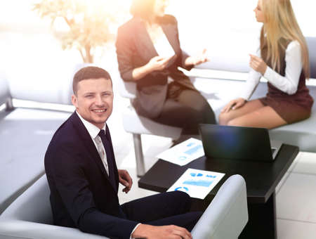 Manager Finance working with documents on the background of colleagues.