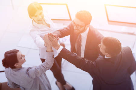 successful business team giving each other a high-five, standing in the officeの写真素材