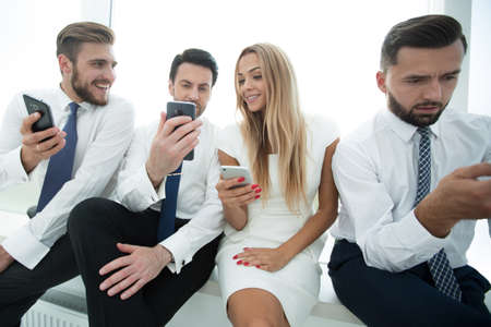close up.Business people using smartphones sitting in a row