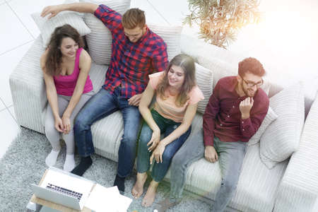 triumphant group of friends laughing while sitting on the couch in the living room
