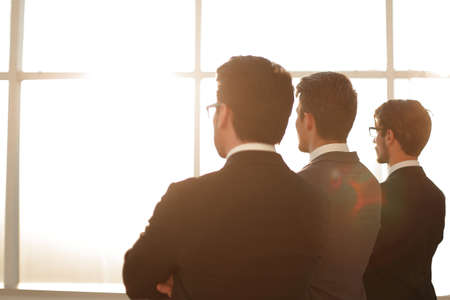 rear view.a group of business people looking out the office windowの写真素材