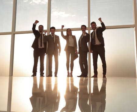 Business group holding hands up near the windowの写真素材