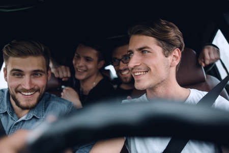 A group of people inside a car, on a road trip