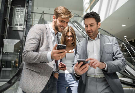 group of young businessmen looking at the screens of their smartphonesの写真素材