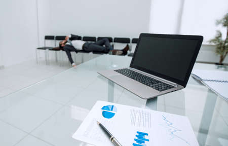 background image of a laptop on a glass table in an empty office