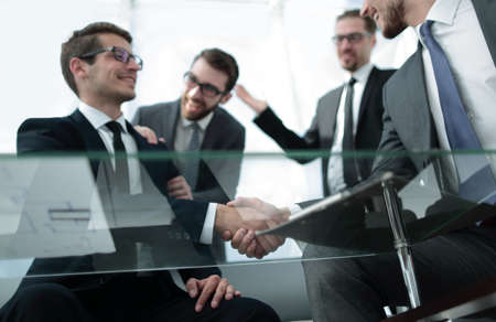 bottom view.business partners shaking hands sitting at the Deskの写真素材