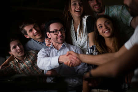 boss shaking hands with company employee at the Desk