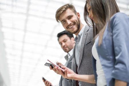 side view.business team looking at the screens of their smartphone
