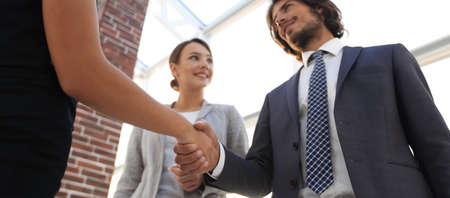 Businesspeople  shaking hands against room with large window loo