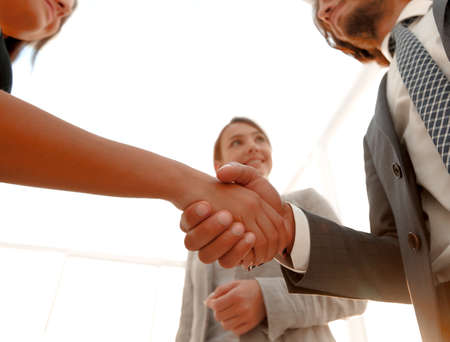 Businesspeople  shaking hands against room with large window loo