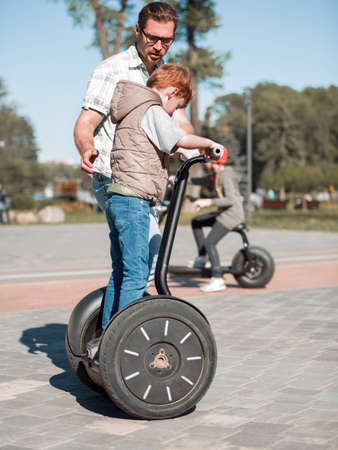father teaches son to ride a mini-hoverboard in the Park