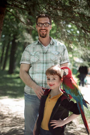 Portrait of father and son with macaw parrot