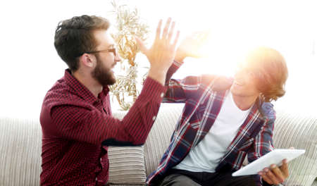 wo guys sitting on the couch and giving each other five