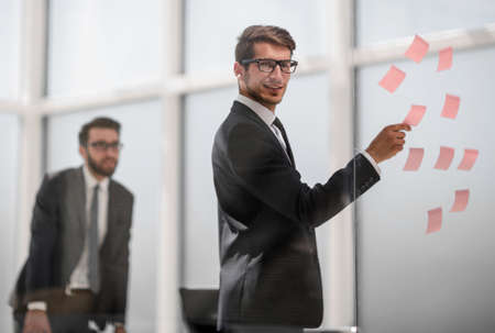 employee reads sticky-notes on glass.