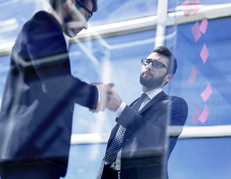 employees standing near a transparent office wall.の写真素材