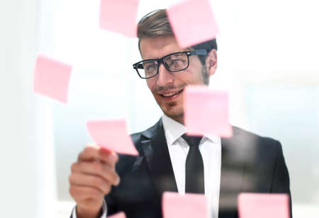 businessman reading sticky notes on the glass