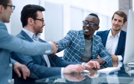 handshake colleagues sitting at the Desk