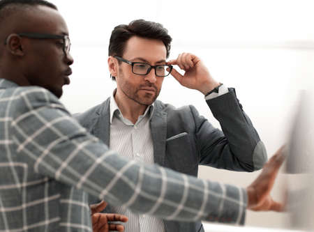 two serious businessmen talking standing in the officeの写真素材