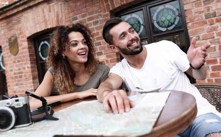 Young  tourists drinking coffee at cafe and reading city mapの写真素材