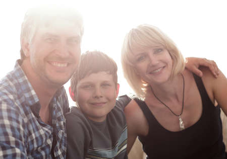 Parents and their son sit huddled in the living room and smiling
