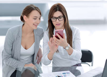 two business women looking at the smartphone screenの写真素材