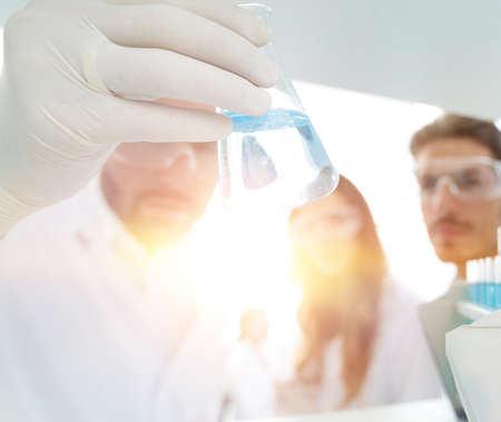 closeup.a group of scientists studying the liquid in the glass tube