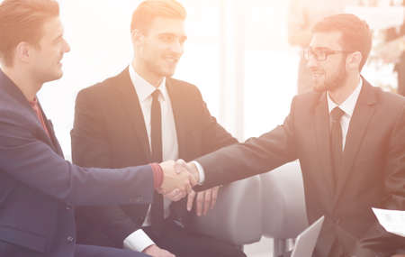 Partners concluding deal and shaking hands in the presence of team membersの写真素材