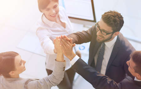 successful business team giving each other a high-five, standing in the office