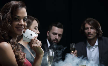 young brunette woman playing poker on black backgroundの写真素材