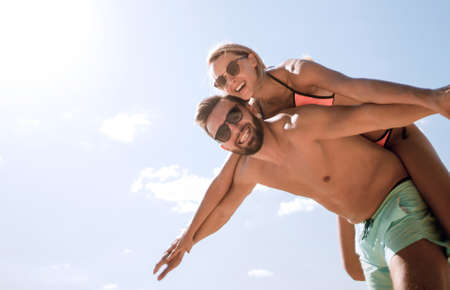 Man carrying woman piggyback on beach.の写真素材