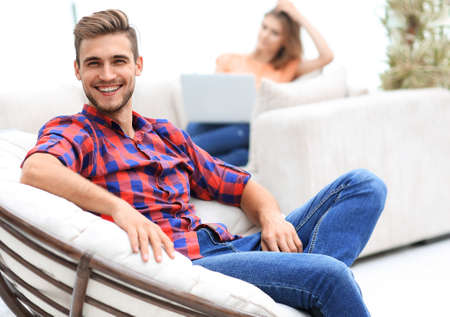 smiling young male sitting in a big chairの写真素材