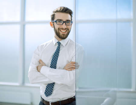 smiling businessman standing near the office window.の写真素材