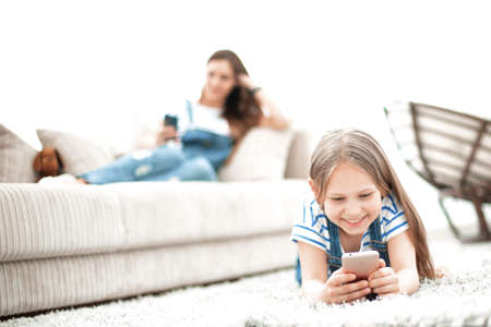background image.mom and her daughter using their smartphones in their home