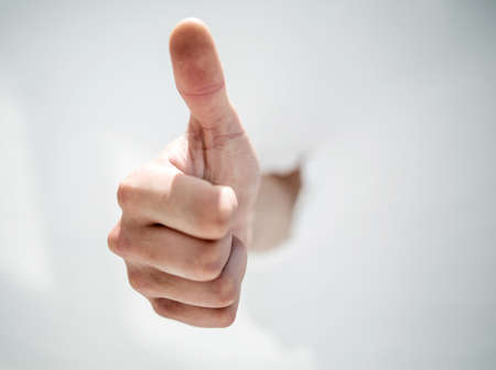 close up.a mans hand breaking through the paper and pointing soの写真素材