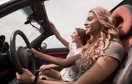 side view.two happy girls riding in the car.の写真素材