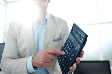 confident businessman pointing to calculatorの写真素材