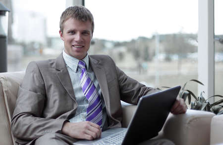 Young businessman sitting at office lobby working with laptop