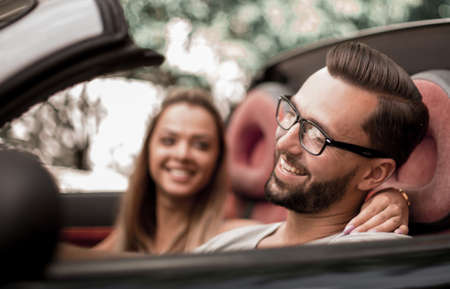 young couple inside a convertible car for a day trip.の写真素材