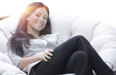 Modern young woman sitting in a round cozy soft chairの写真素材