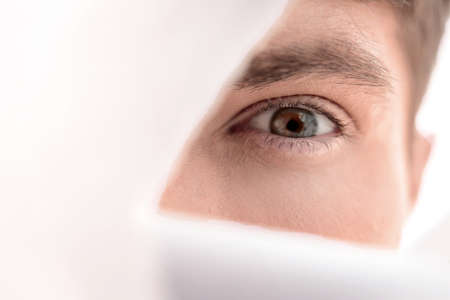 close up.guy looking through a hole in the paper.の写真素材