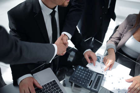 Handshake across the table of financial partners