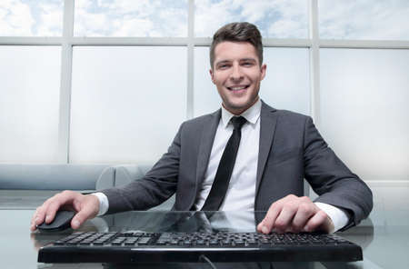 young businessman sitting in his office looking at cameraの写真素材