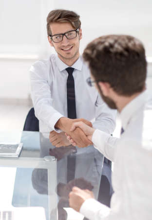 happy employees shake hands while sitting at the Desk.の写真素材